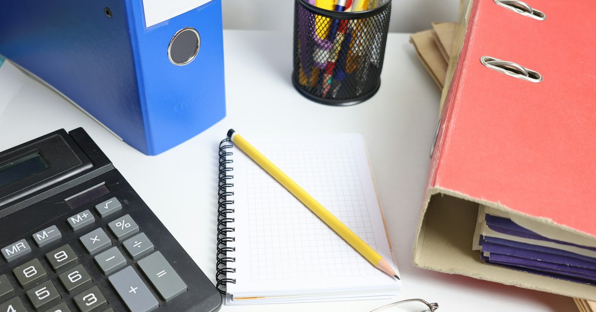 Calculator, notepad and binders on a desk, used to work out German course fees